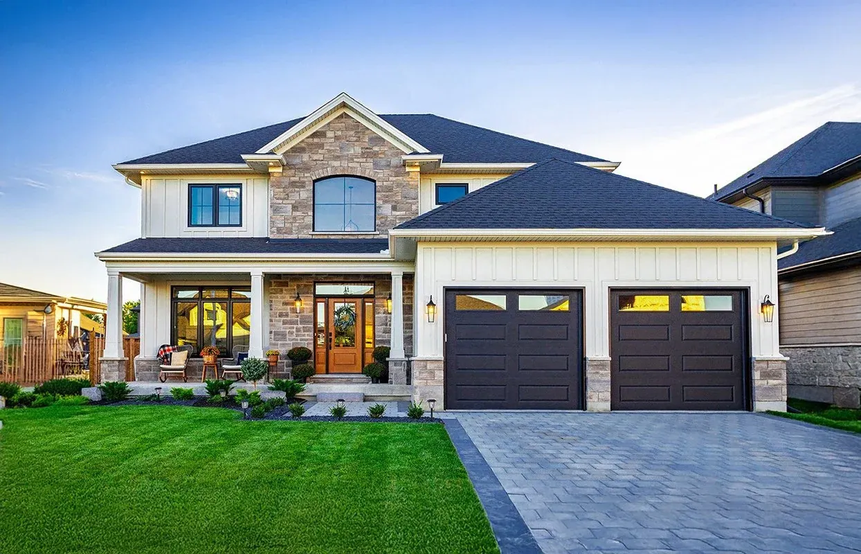 Real estate photograph of a stone and white two-storey home at dusk